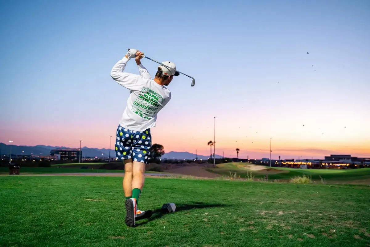 Grass League player mid-swing at sunset on a par-3 hole